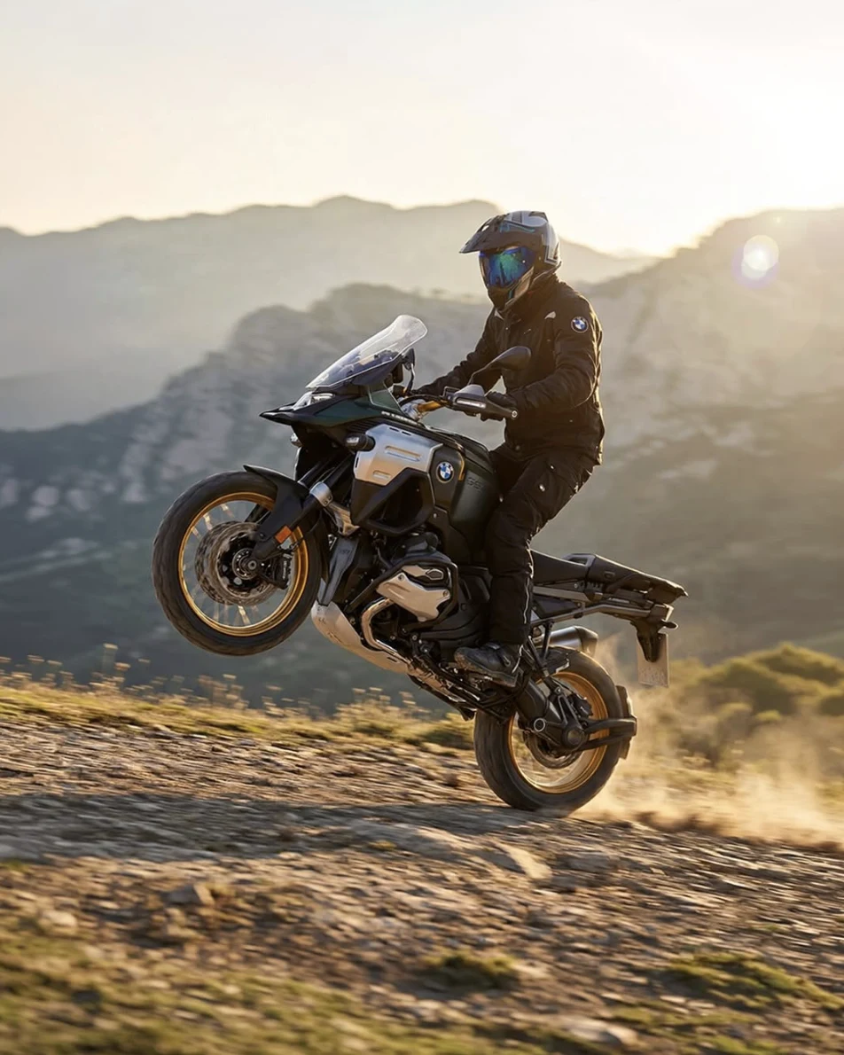BMW GS Adventure en wheelie sobre camino de montaña — el espíritu de Quality Bikes